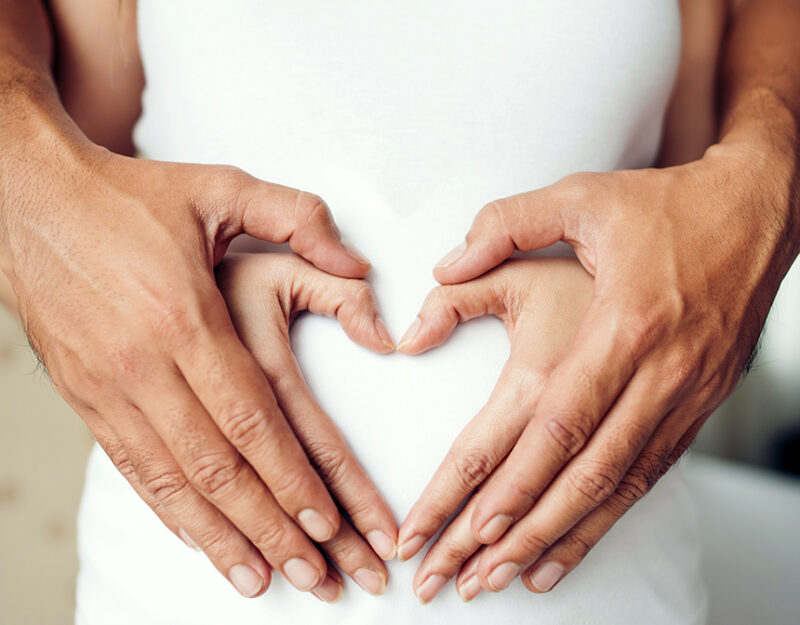 Pregnant Woman and Her Husband hand showing heart shape.